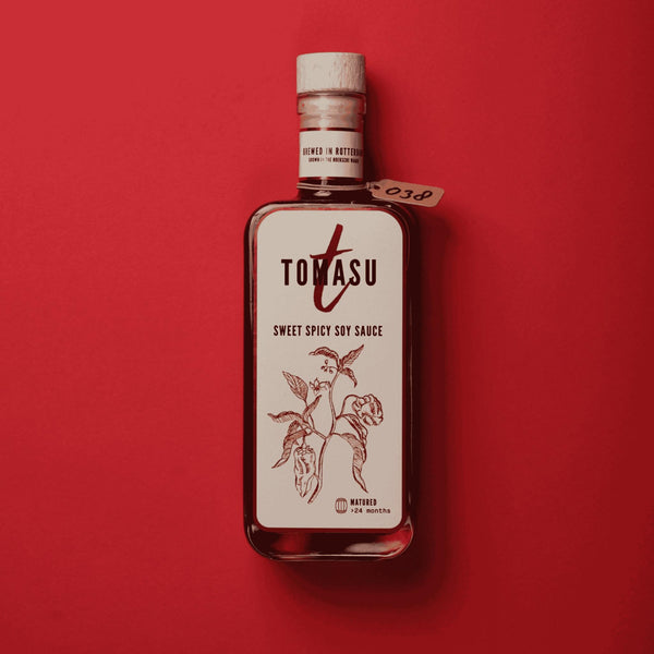 Tomasu Sweet Spicy Sojasauce 100 ml, Flasche mit Holzkorken auf rotem Hintergrund, Etikett mit Chilipflanze