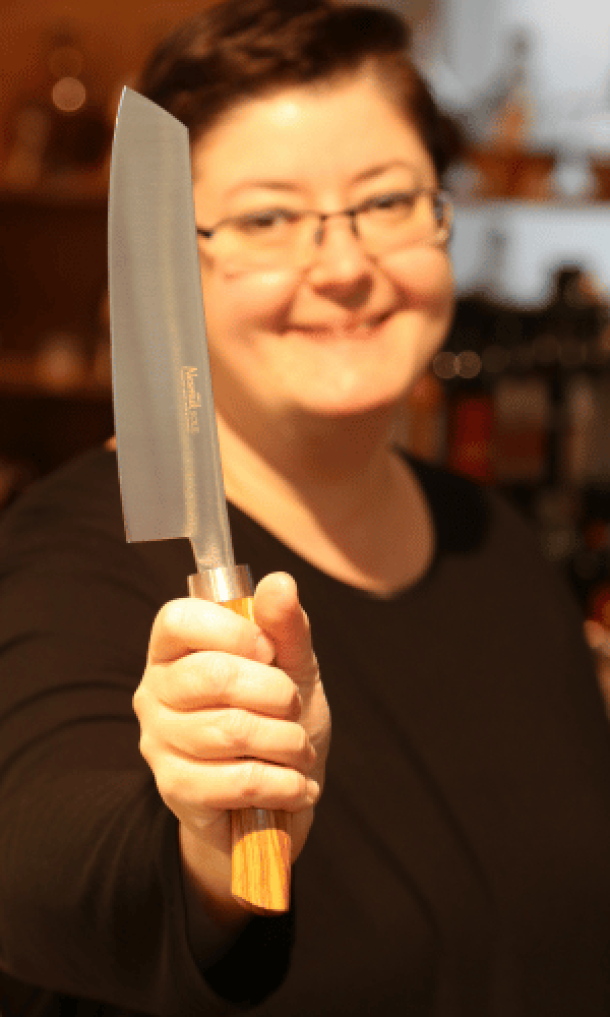 Messerspezialistin hält ein Nesmuk Messer mit Olivenholzgriff in der Hand
