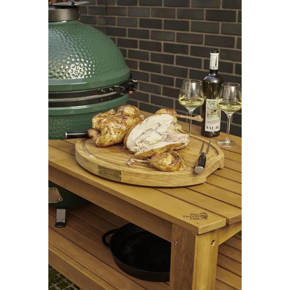 Eukalyptustisch am Big Green Egg mit tranchiertem Hähnchen auf Holzbrett und Weißwein