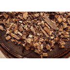 Rippchen auf dem grünen Big Green Egg mit Rauch von Hickory-Chips vor Holzwand