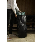 Person befüllt den schwarzen Big Green Egg Aufbewahrungsbeutel mit einem Sack Holzkohle.