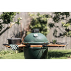 Big Green Egg mit zwei Akazien-Seitentischen, Gusseisentopf und Handschuhen im Garten
