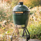 Big Green Egg Large im Nest auf einer Holzterrasse vor herbstlichem Ziergras im Garten.