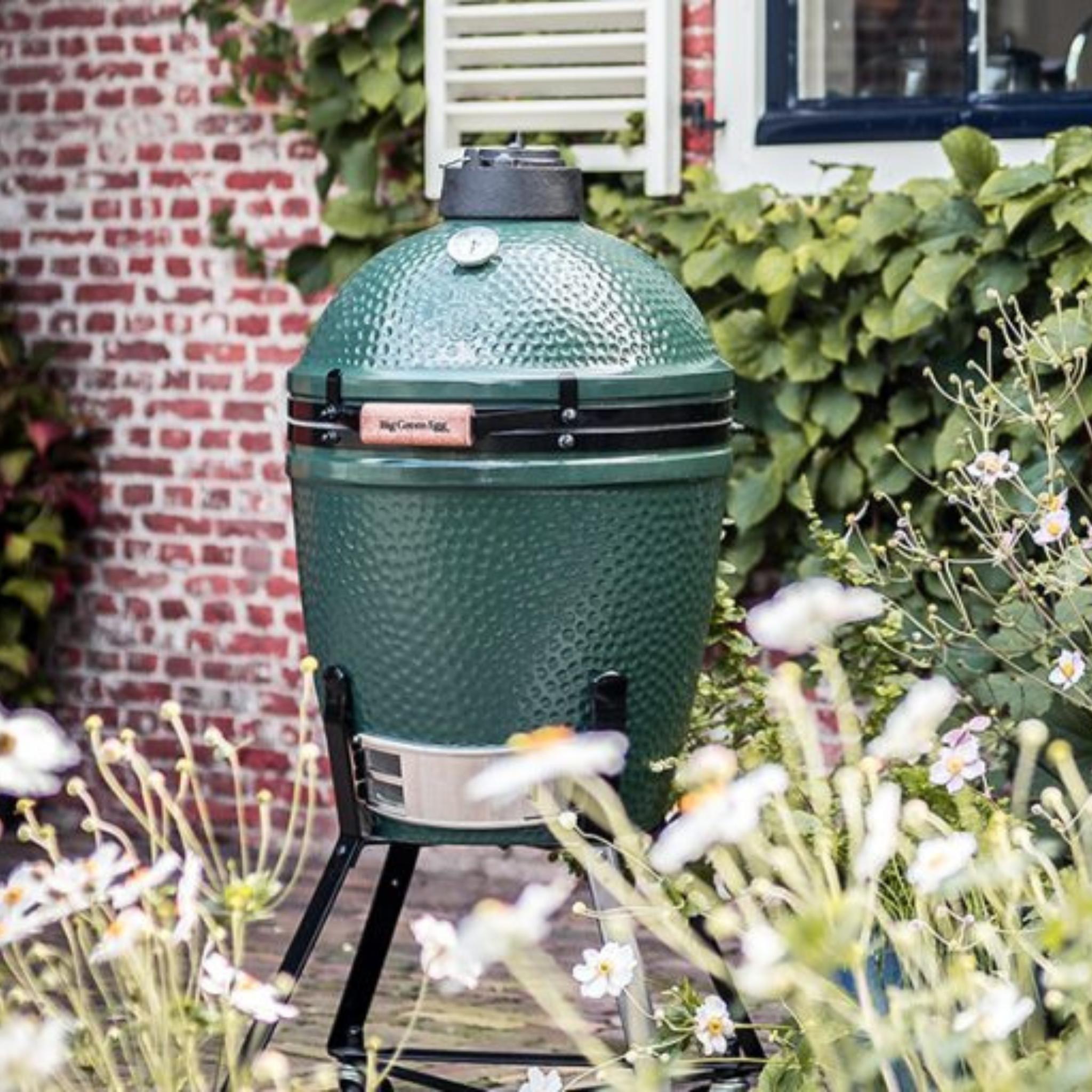 Big Green Egg Medium auf dem Nest im Garten, umrahmt von weißen Bluten