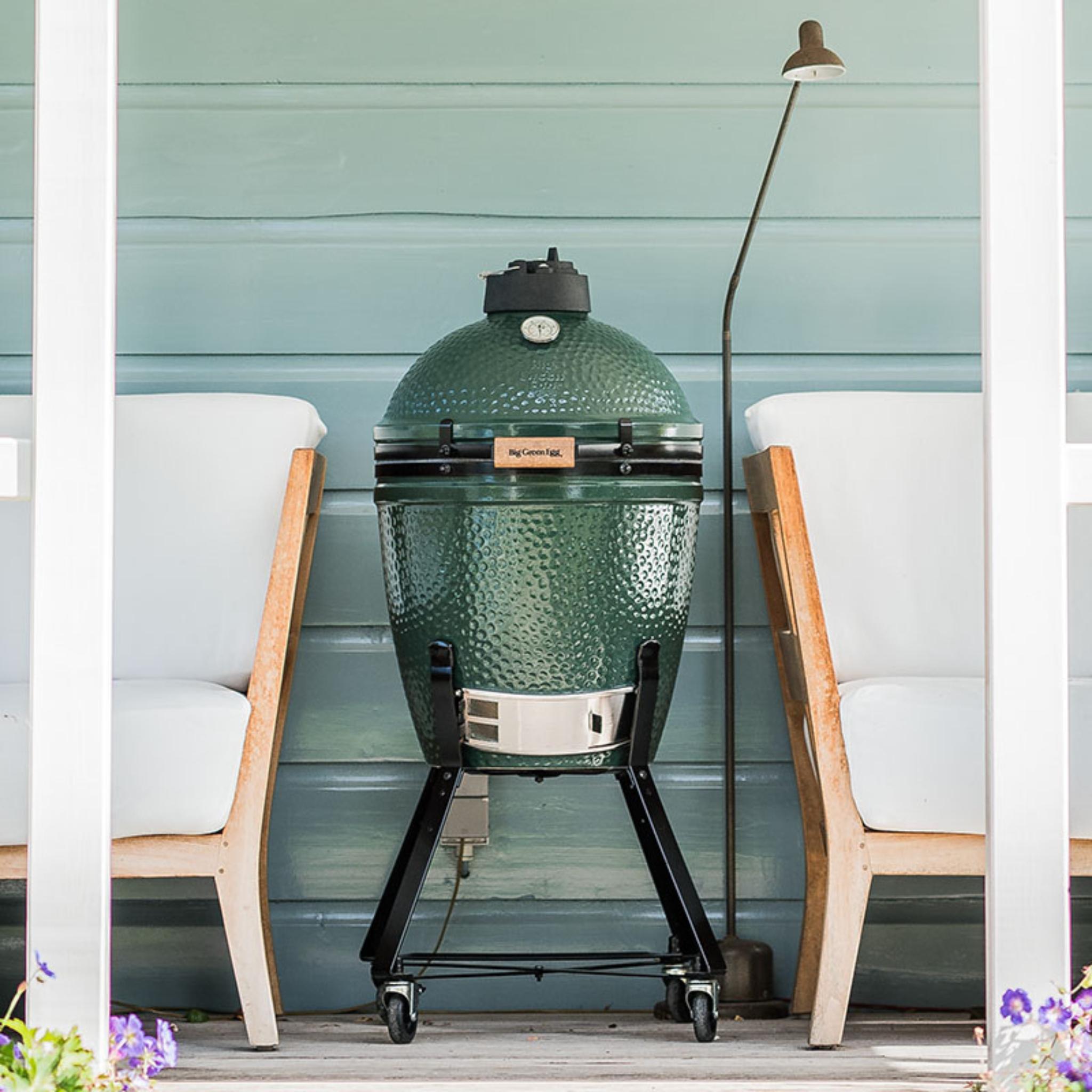 Big Green Egg Medium auf fahrbarem Nest zwischen zwei Loungesesseln auf der Terrasse