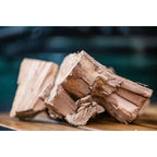 Nahaufnahme grober Mesquite-Holzchunks von Big Green Egg auf einem Holzbrett