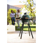 MiniMax Big Green Egg mit Akazien-Seitentischen im sonnigen Garten, Personen im Hintergrund