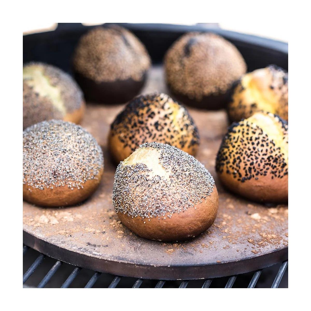 Mehrere Mohnbrötchen mit knuspriger Kruste backen auf dem Big Green Egg Pizzastein im Grill.