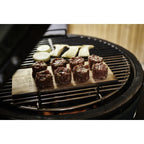 Gewürzte Fleischstücke auf einer Zedernholz-Grillplanke auf dem Big Green Egg Rost