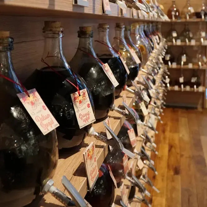 Reihe handbeschrifteter Glasballons mit hochwertigen Ölen und Essigen zum Abfüllen – nachhaltig genießen bei Miori Feinkost