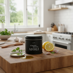 miori Aioli Dose auf Holzbrett in heller Küche, daneben halbe Zitrone, Knoblauch und Olivenöl im Schälchen
