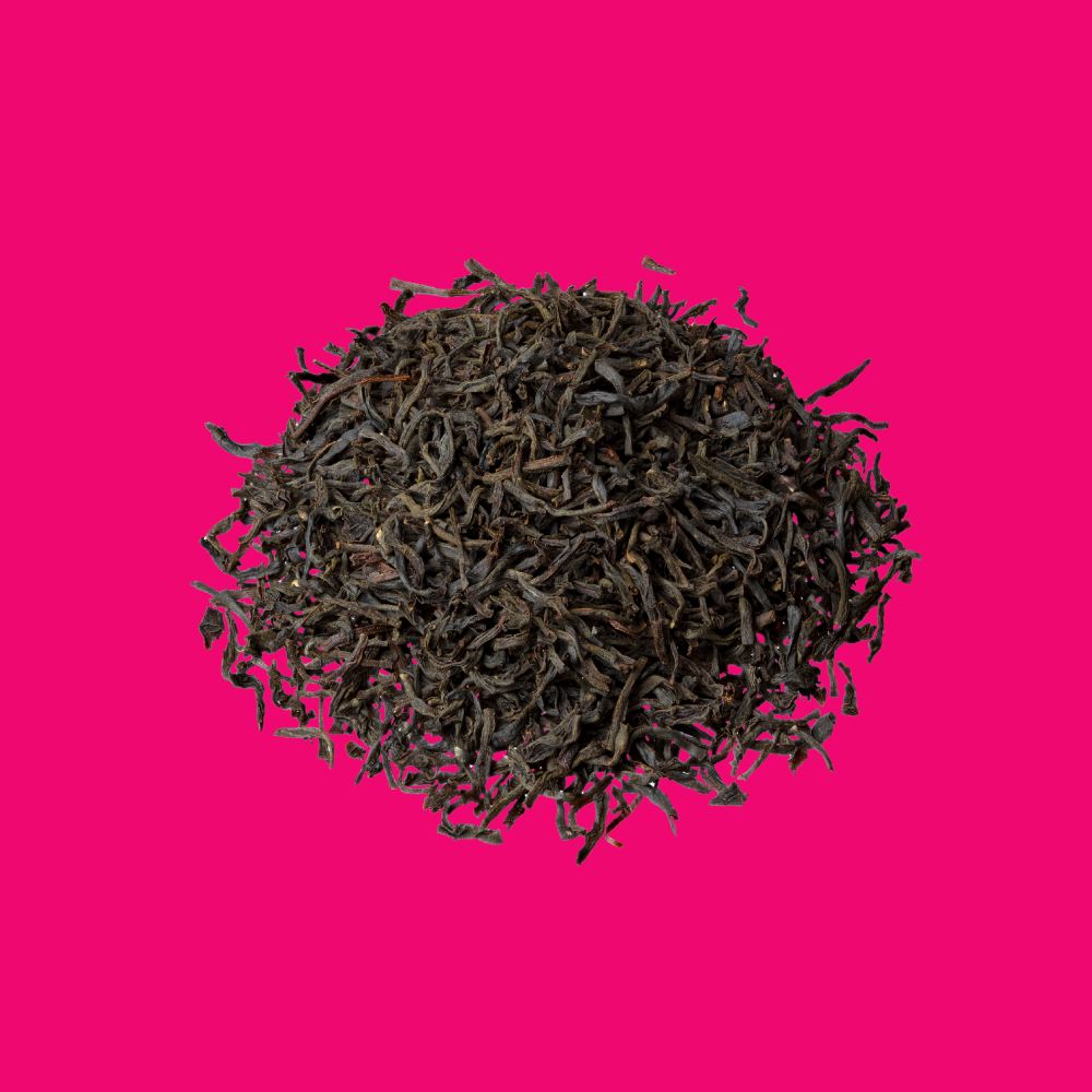 Schüttbild Earl Grey Imperial, dunkle Schwarzteeblätter rund angeordnet auf pinkem Hintergrund