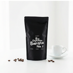 Bio Espresso Barista No. 1 Beutel vor weißem Hintergrund neben Espressotasse und verstreuten Kaffeebohnen