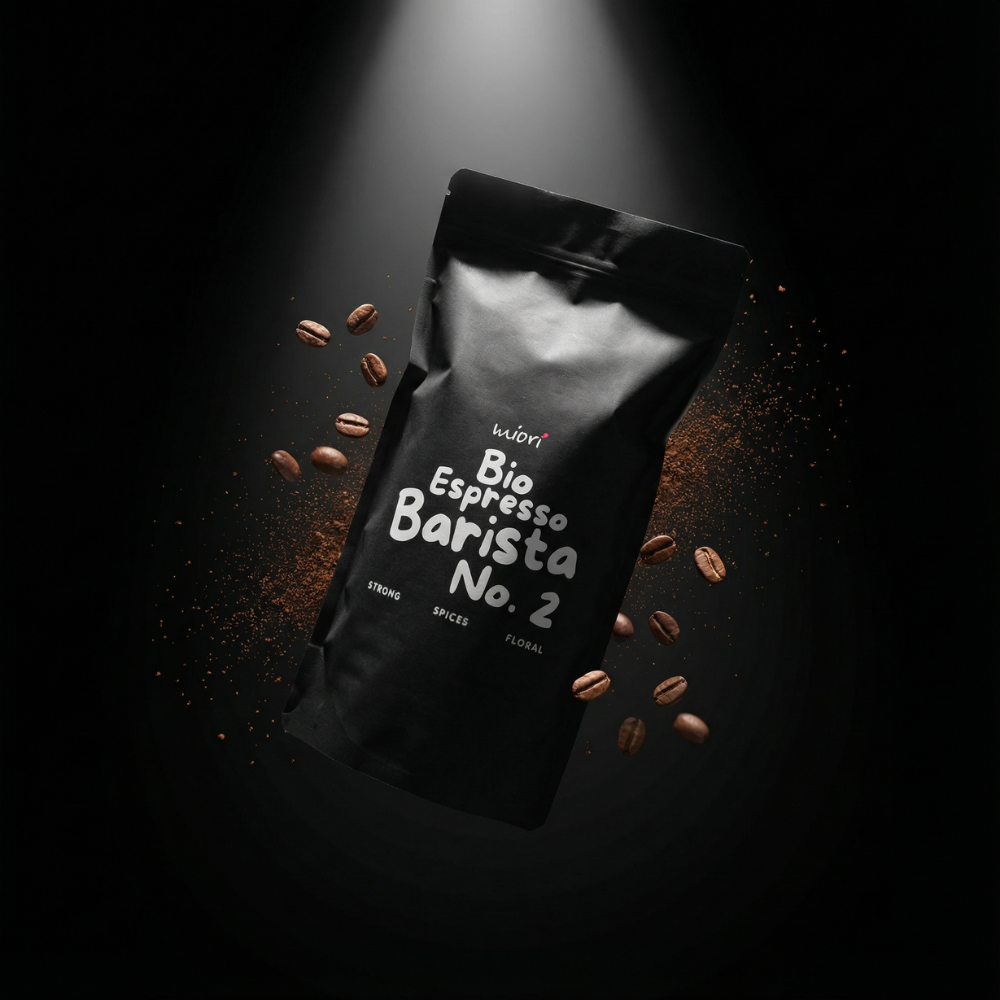 Schwarzer Bio Espresso Barista No. 2 Beutel von miori liegend zwischen Kaffeebohnen und Pulver im Spotlight