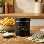 Pommes Glück Gewürzsalz Dose auf Holztisch, daneben Schale mit Pommes, grobes Salz und Rosmarinzweig