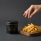 Pommes Glück Dose vor grauem Hintergrund, Hand salzt einen Haufen Pommes frites auf Holzbrett