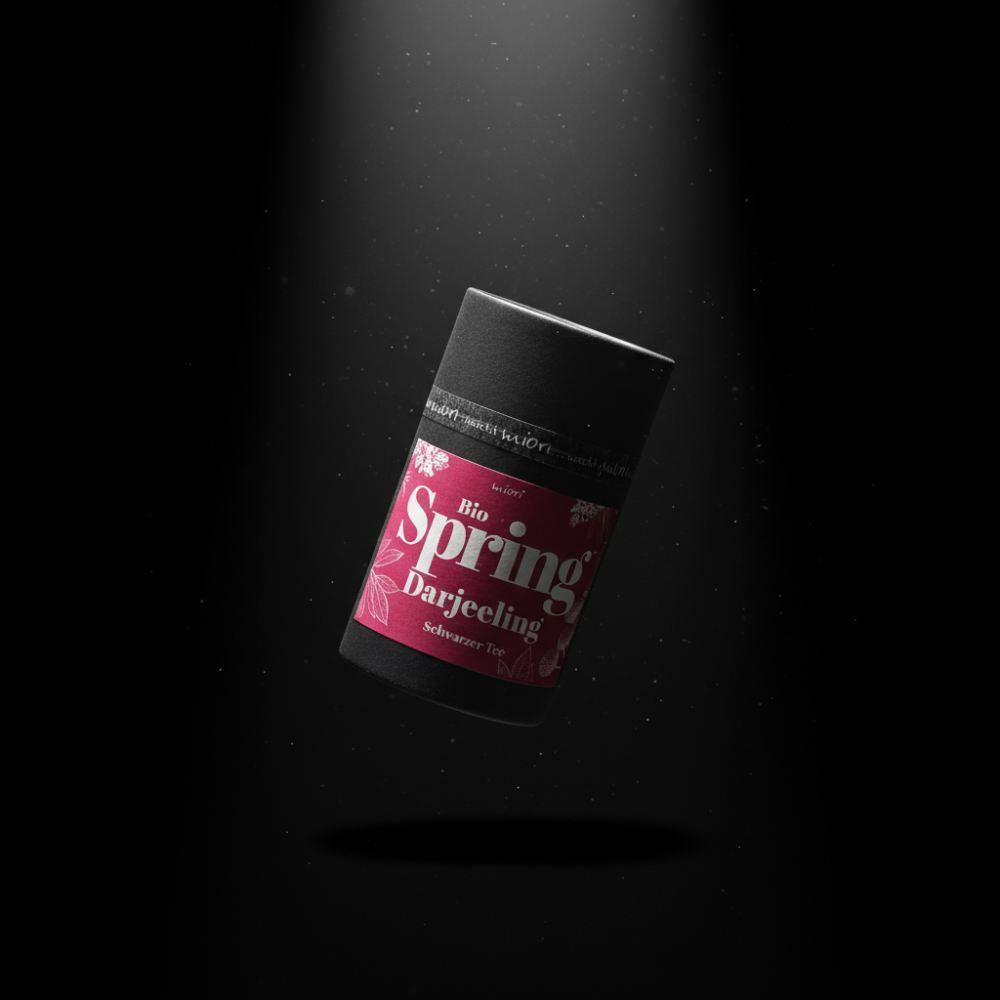 Bio Spring Darjeeling Teedose mit pinkem Etikett, schwebend vor schwarzem Hintergrund