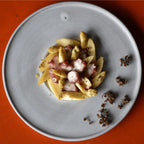 Pulpo mit weißem Spargel auf grauem Teller, dazu Andaliman-Beeren der Rosenheimer Gewürzmühle, oranger Hintergrund