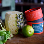 Geschälte Ananas, Limette und Basilikum neben zwei orangen Dosen Honeyballs Dessert Rub auf Holzbrett