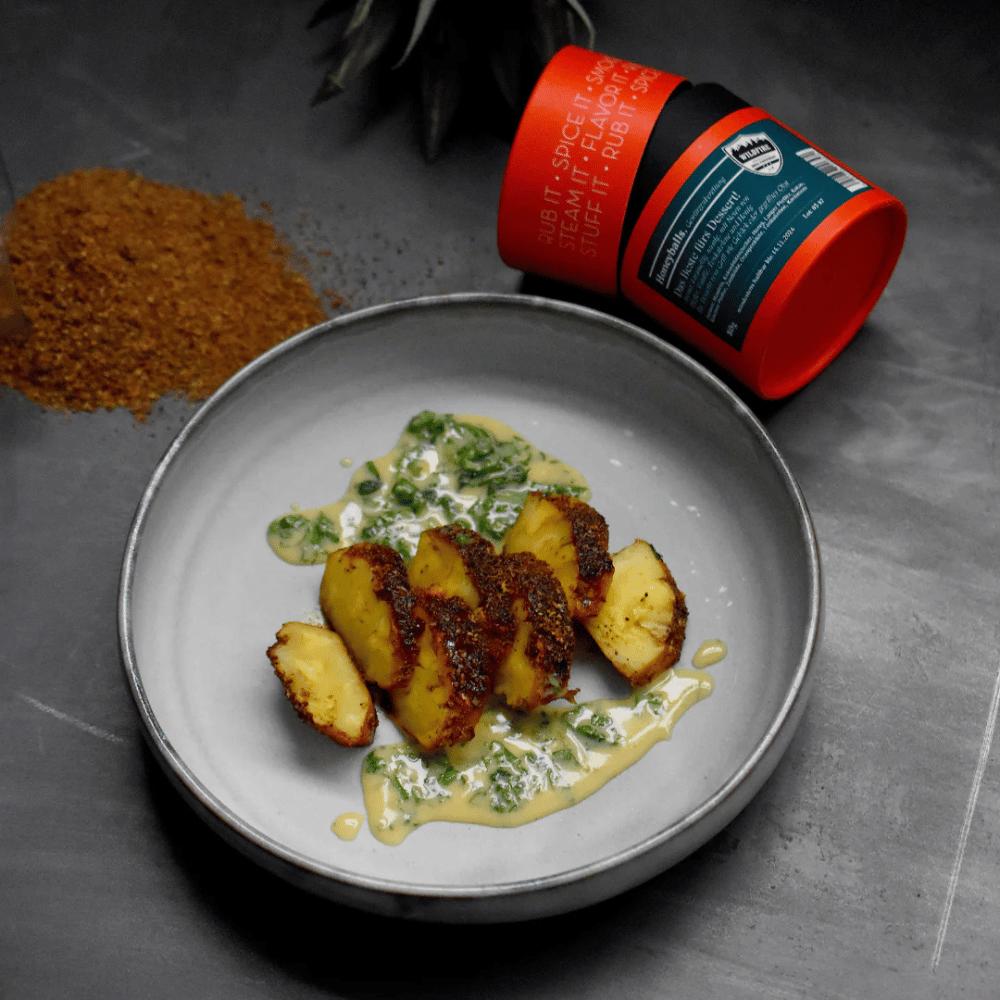 Gegrillte Ananasstücke mit Honeyballs Dessert Rub und cremiger Sauce auf grauem Teller, Dose der Rosenheimer Gewürzmühle daneben