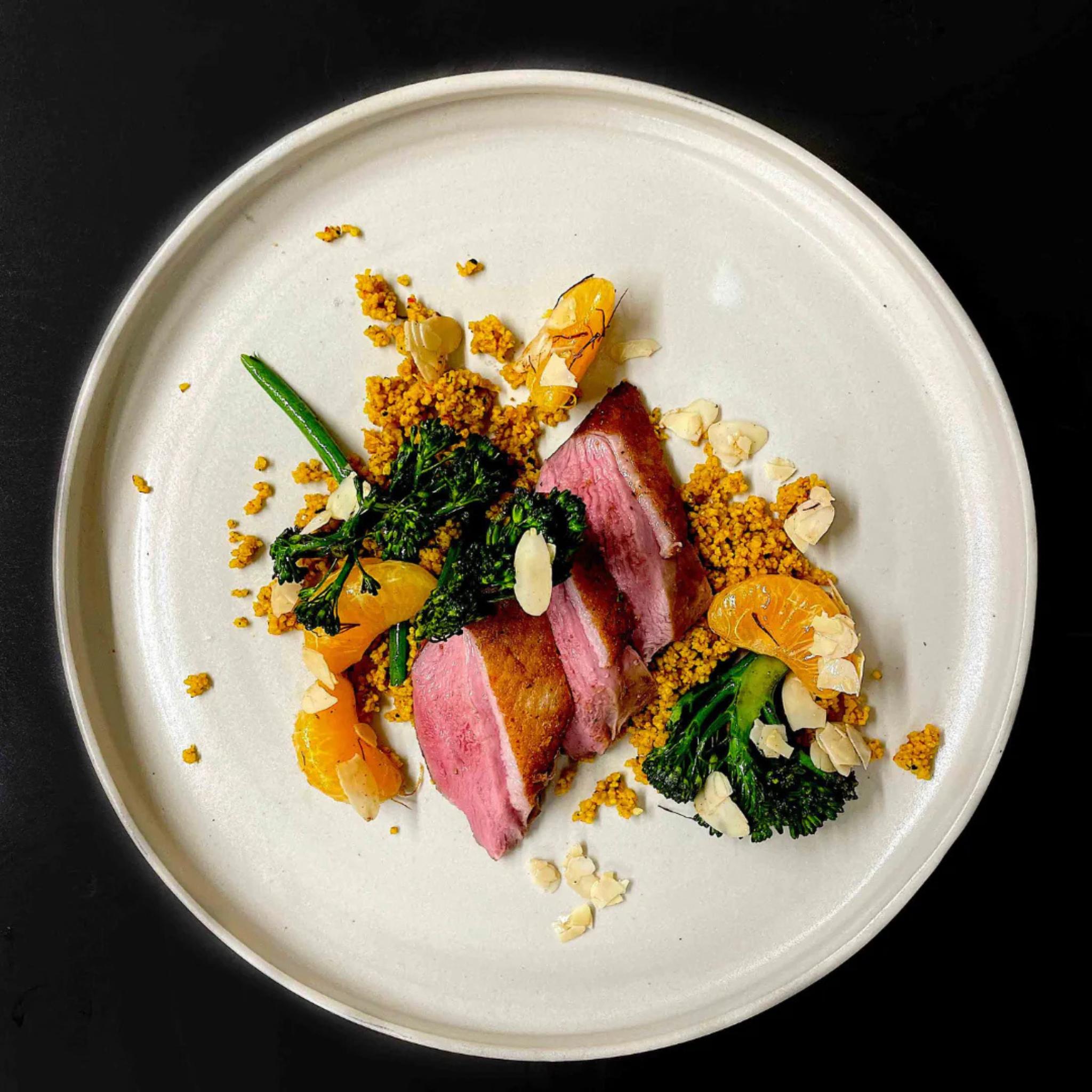 Rosa gebratene Entenbrust mit Brokkolini, Mandarine und Couscous auf weißem Teller, gewürzt mit Korean S(e)oul Rub