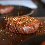 Dickes Steak auf Holzbrett wird mit Korean S(e)oul Rub aus Sesam und Chiliflocken bestreut