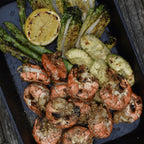 Gegrillte Garnelen mit gegrillter Zitrone, grünem Spargel und Avocado auf dunkler Gusseisenplatte, Orange Ocean Rub