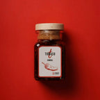 Tomasu Sambal 165 g im Glas mit Holzdeckel auf rotem Hintergrund, fermentierte Chilipaste mit weißem Etikett