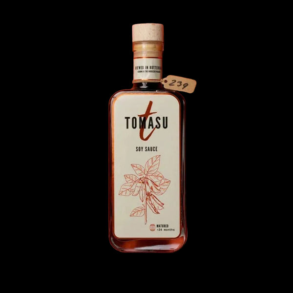 Tomasu Sojasauce 100 ml in der Glasflasche mit Holzkorken vor schwarzem Hintergrund, Etikett mit Sojapflanze, über 24 Monate gereift