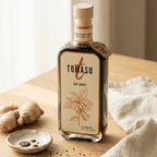 Tomasu-Sojasauce-Flasche auf einem Holztisch, daneben frischer Ingwer und ein kleines Schälchen