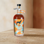Windspiel Alkoholfrei Spritz 0,5 l, Flasche mit orange-rotem Getränk, Etikett mit Zitrusblüten-Muster und schwarzem Windhund, auf Steinplatte