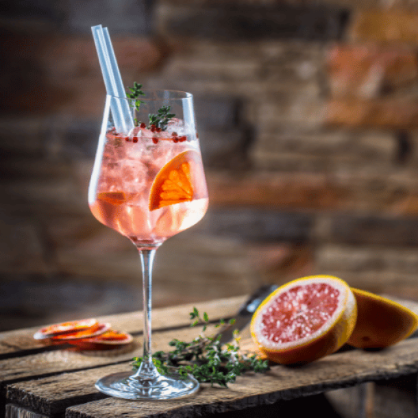 Glas mit Gin, garniert mit rotem Pfeffer und frischen Blutorangenscheiben, das eine lebendige und pikante Geschmackskomposition für einen erfrischenden Cocktail darstellt.