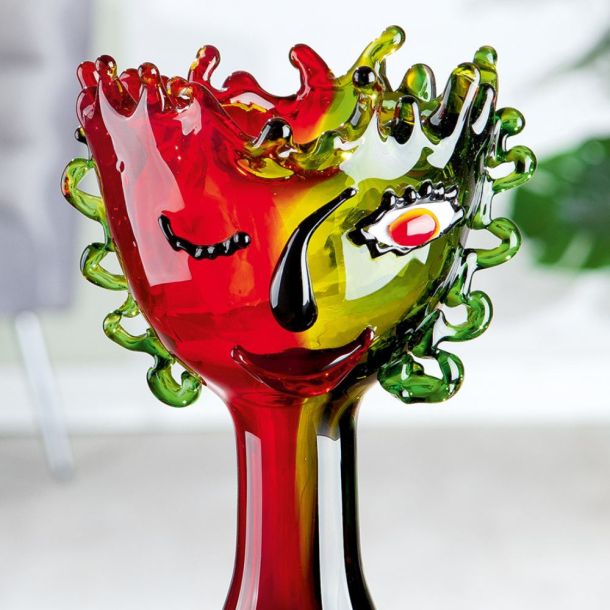 Farbenfrohe Glaskunst-Skulptur mit abstraktem Gesichtsmotiv in Rot, Grün und Gelb, die Dynamik und Kreativität ausstrahlt.