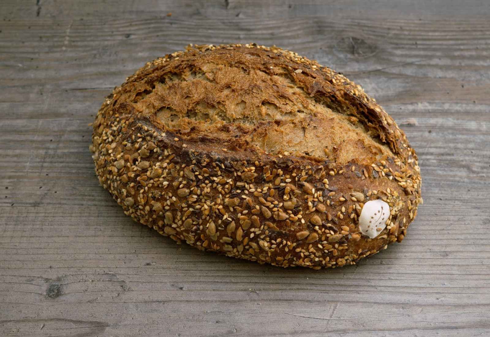 Bio Omega Brot reich bestreut mit einer Vielfalt an Saaten und Samen auf Holzuntergrund.