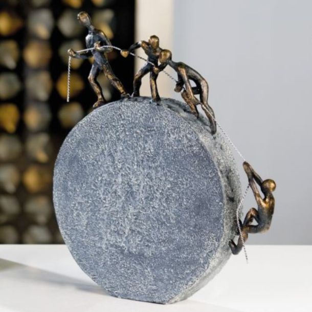 Abstrakte Skulptur mit fünf Figuren, die gemeinsam einen großen steinähnlichen Kreis bewegen, symbolisch für Teamarbeit und Kooperation gezeigt bei miori