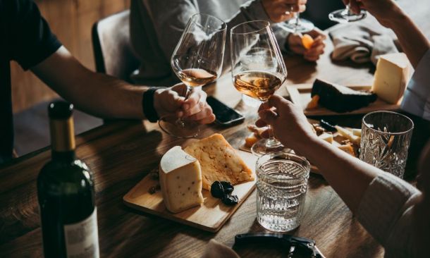 Menschen genießen Miori-Käse und Wein an einem modernen Tisch, ein Moment des Genusses und der Geselligkeit.